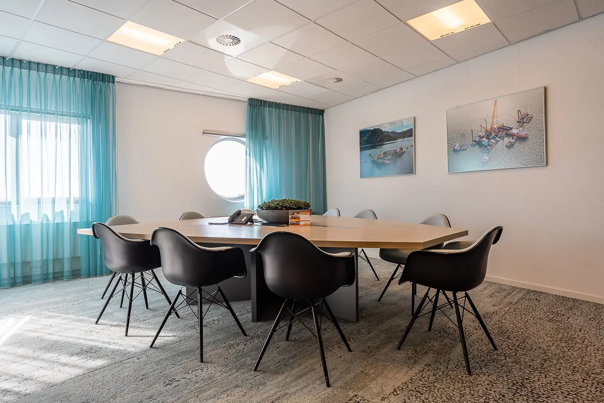 Vergaderruimte in Rivium Quadrant met moderne inrichting, zwarte stoelen en wanddecoratie met maritieme foto's.